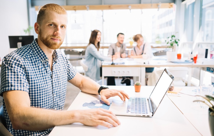 Man working on a laptop in a commercial office setting where indoor air quality matters